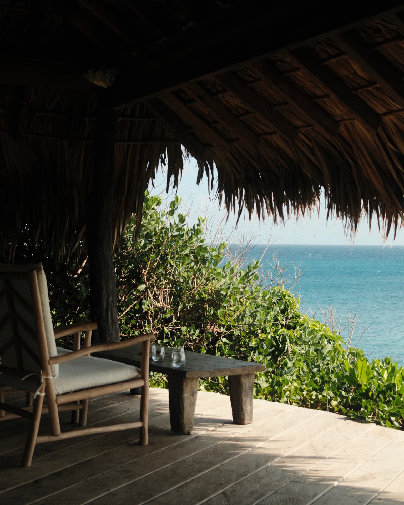 Thatched terrace with teak chairs overlooking the ocean