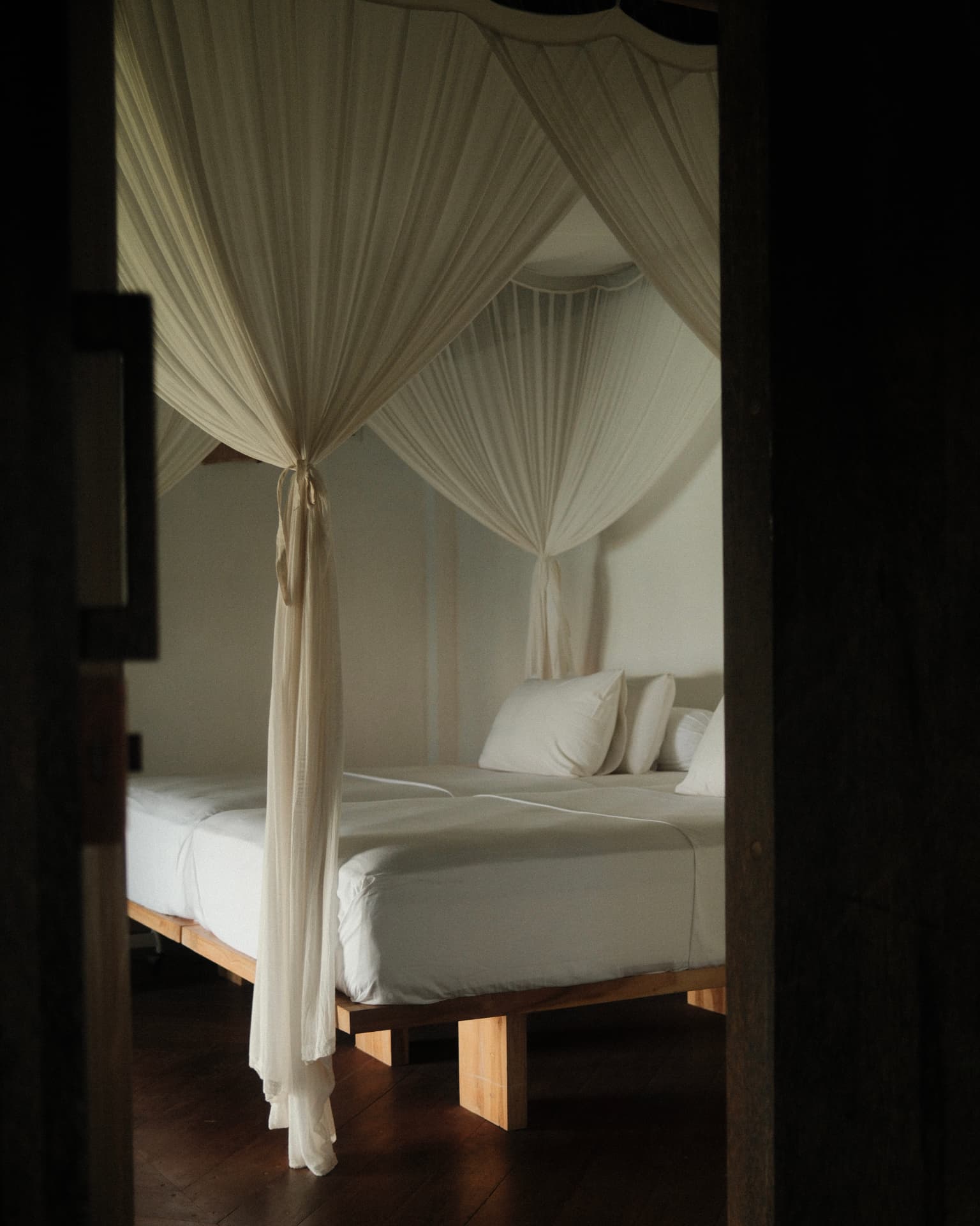 Canopy bed with linen drapes seen through a doorway